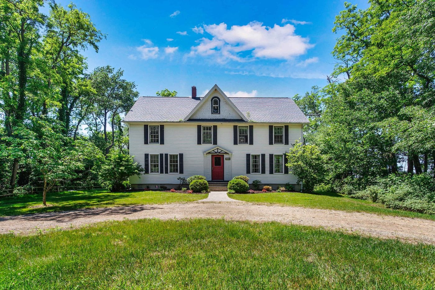 A white farmhouse with a red door on a wide green lawn in South Haven, Michigan
